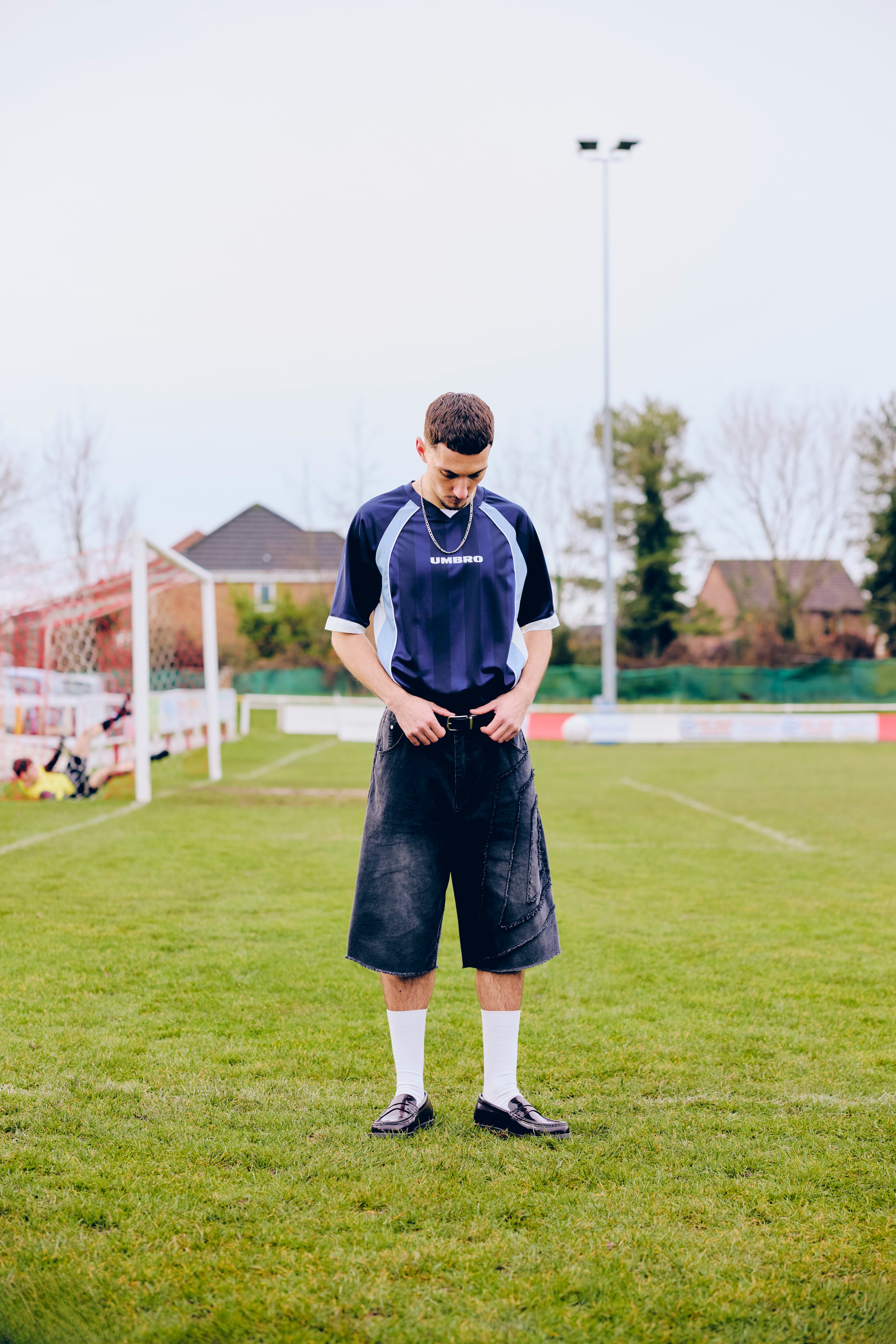 Person standing on a grassy field wearing a Umbro shorts.